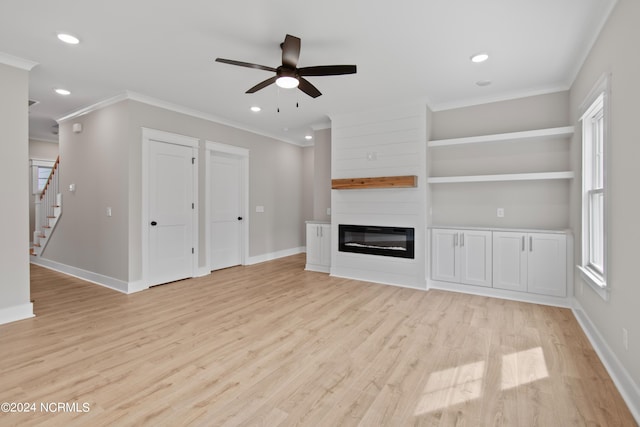 unfurnished living room featuring light hardwood / wood-style flooring, ornamental molding, a large fireplace, and ceiling fan