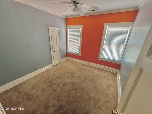 unfurnished room featuring crown molding, visible vents, a ceiling fan, carpet flooring, and baseboards