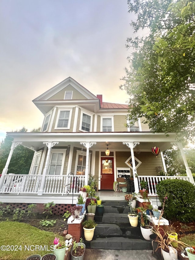 victorian house featuring a porch, a standing seam roof, and metal roof