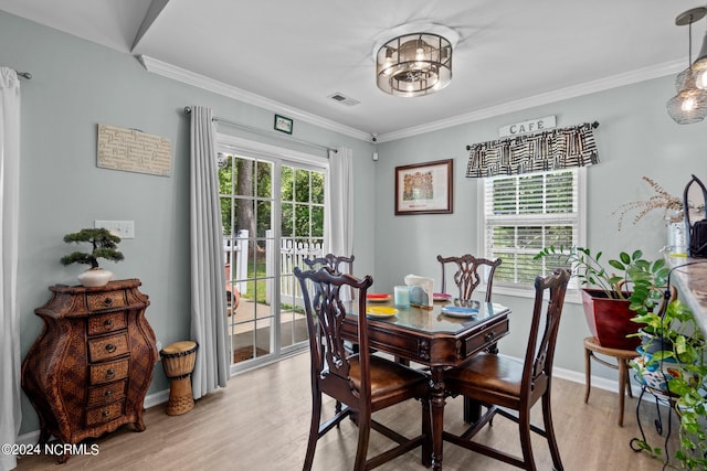 dining area featuring light wood-type flooring and crown molding