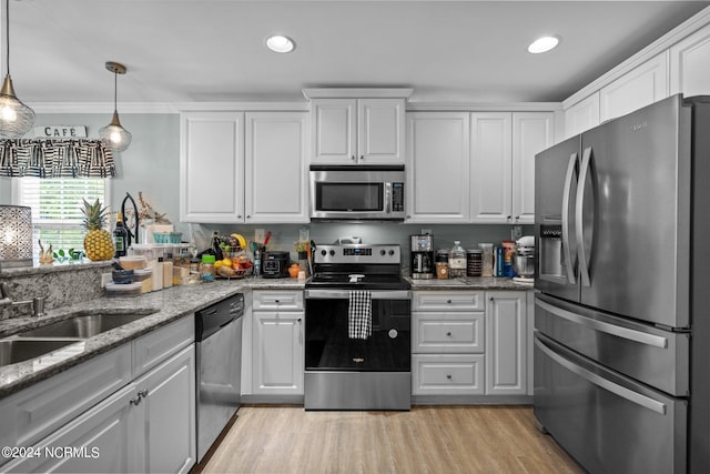 kitchen featuring light hardwood / wood-style flooring, white cabinets, appliances with stainless steel finishes, light stone counters, and crown molding