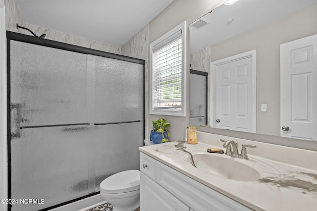 bathroom with a shower with door, toilet, and vanity