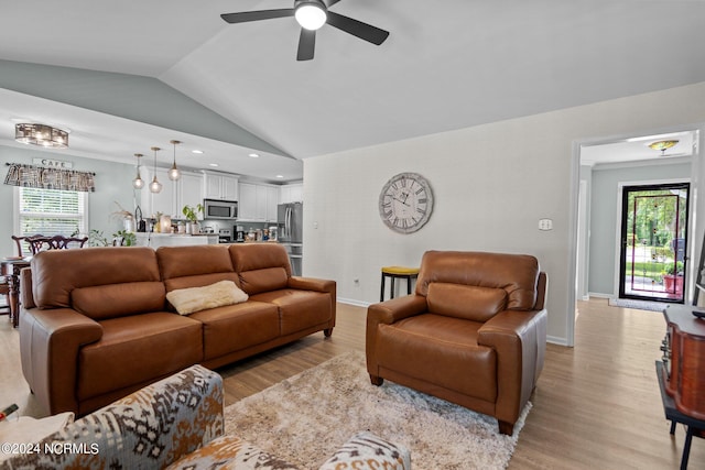 living room with high vaulted ceiling, ceiling fan, and light wood-type flooring