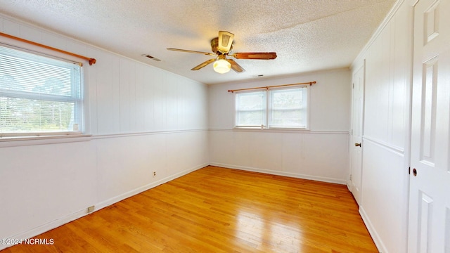 unfurnished room with ceiling fan, plenty of natural light, light hardwood / wood-style flooring, and a textured ceiling