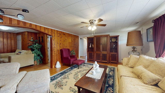 living room featuring wooden walls, ceiling fan, and light hardwood / wood-style flooring