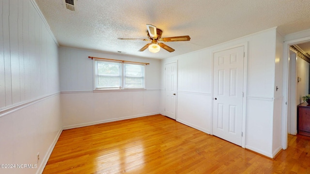 unfurnished bedroom featuring crown molding, ceiling fan, a textured ceiling, and light wood-type flooring