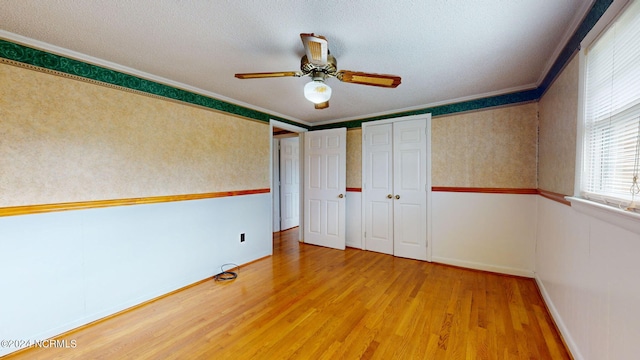 unfurnished bedroom featuring crown molding, light wood-type flooring, and ceiling fan