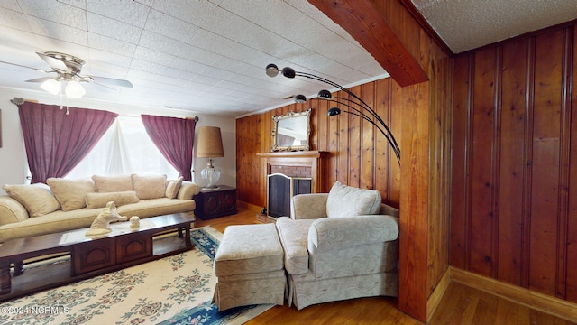 living room featuring wood walls, hardwood / wood-style floors, ceiling fan, and a fireplace