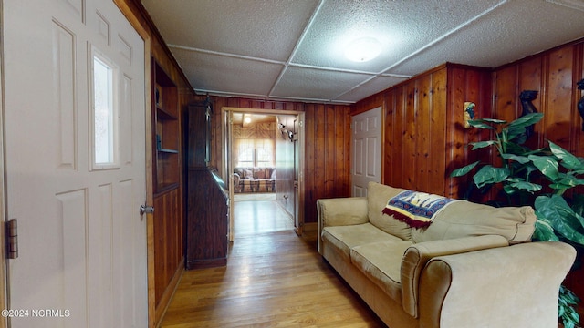 living room with a wealth of natural light, wooden walls, and light hardwood / wood-style flooring