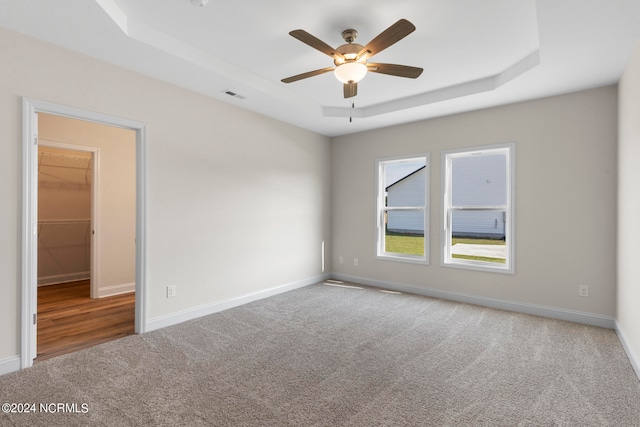 carpeted empty room with ceiling fan and a tray ceiling