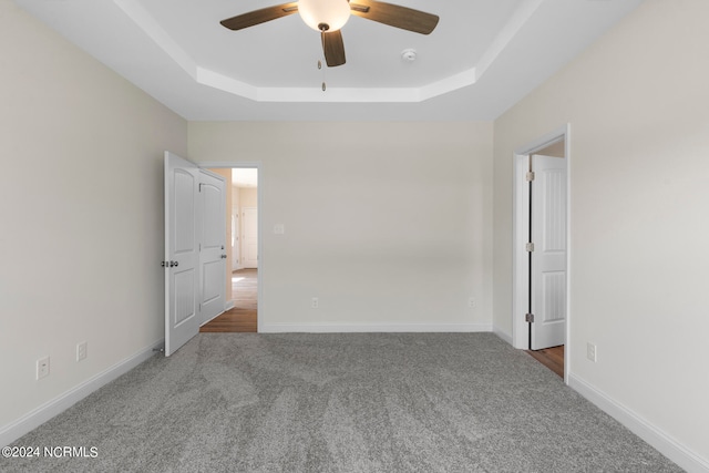 unfurnished room with carpet, a tray ceiling, and ceiling fan