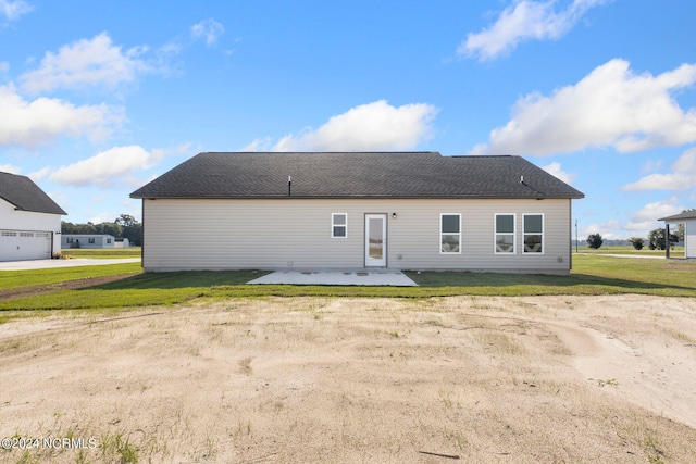 rear view of house with a garage, a patio area, and a yard