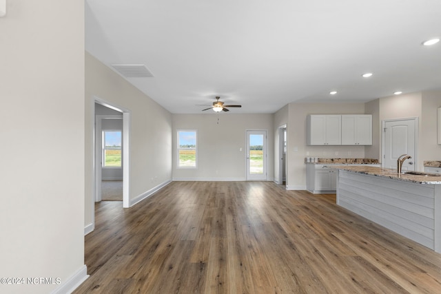 unfurnished living room with ceiling fan, hardwood / wood-style flooring, and sink