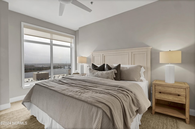 bedroom with ceiling fan, light colored carpet, and multiple windows