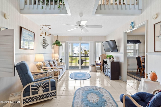 living room with ceiling fan, light tile floors, and a textured ceiling