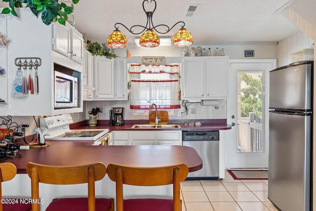 kitchen with stainless steel appliances, white cabinets, sink, and light tile flooring