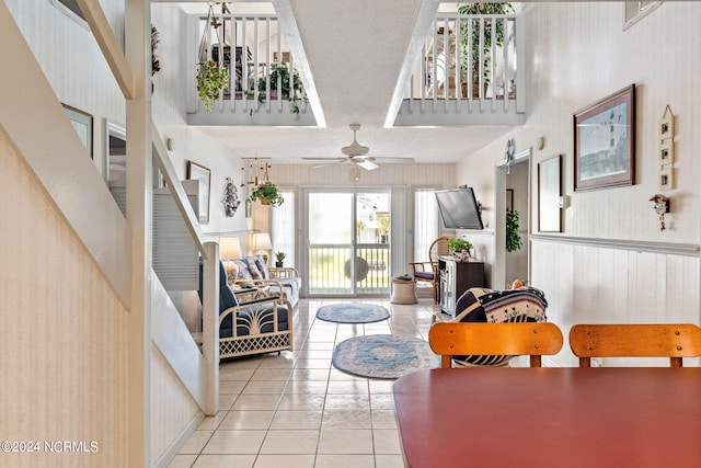 living room featuring tile floors, ceiling fan, and a towering ceiling