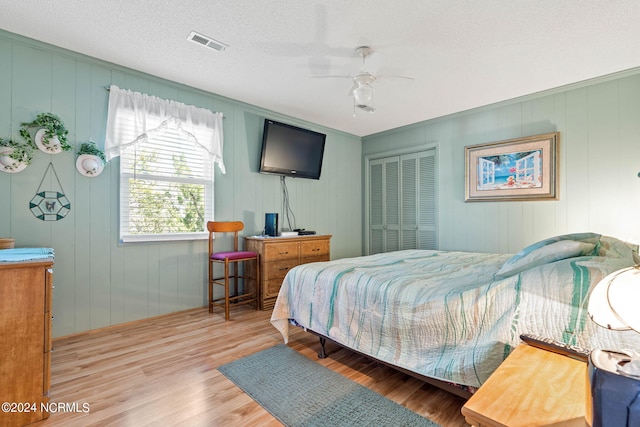 bedroom with a textured ceiling, ceiling fan, a closet, and hardwood / wood-style floors