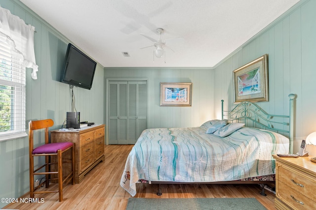 bedroom featuring ornamental molding, a closet, ceiling fan, and light wood-type flooring