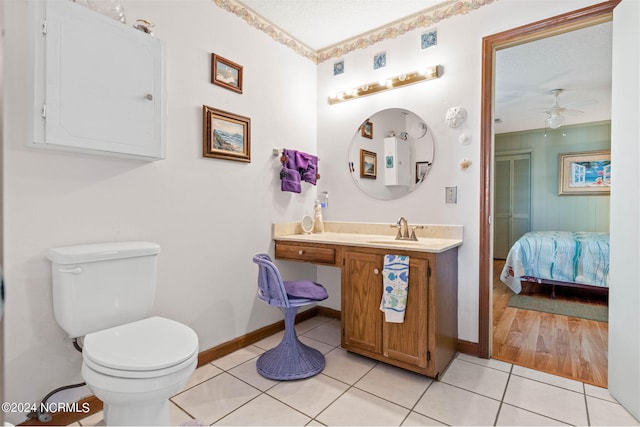 bathroom with ceiling fan, large vanity, a textured ceiling, toilet, and wood-type flooring