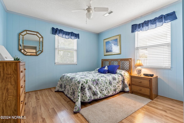 bedroom with ceiling fan, light wood-type flooring, and a textured ceiling