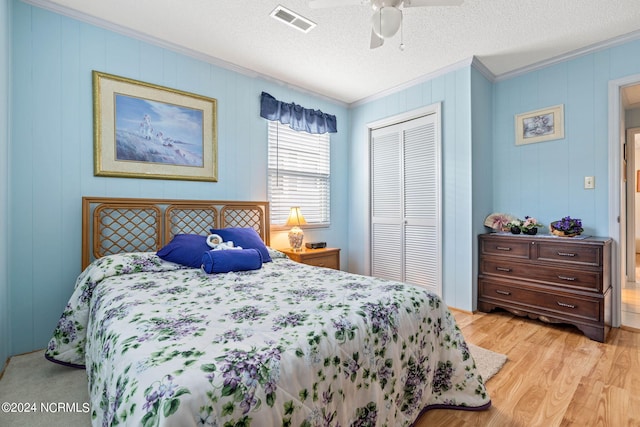 bedroom with a closet, ceiling fan, a textured ceiling, light hardwood / wood-style floors, and crown molding