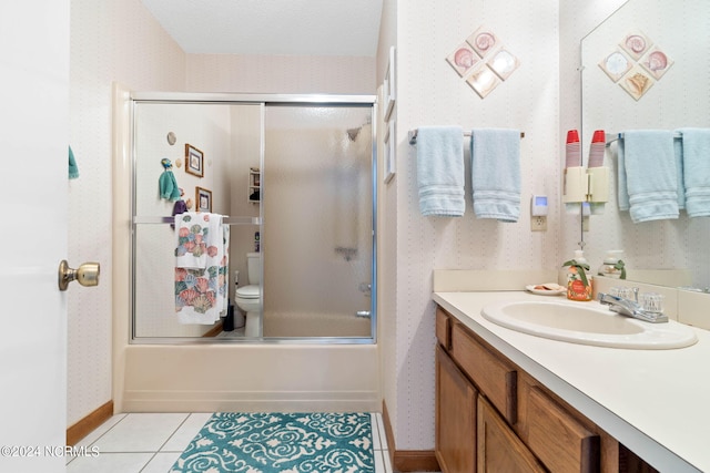 full bathroom featuring tile flooring, oversized vanity, toilet, and bath / shower combo with glass door