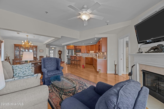 living room with ceiling fan with notable chandelier and light wood-type flooring