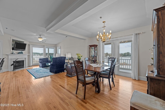 dining room featuring ceiling fan with notable chandelier, plenty of natural light, beamed ceiling, and light wood-type flooring