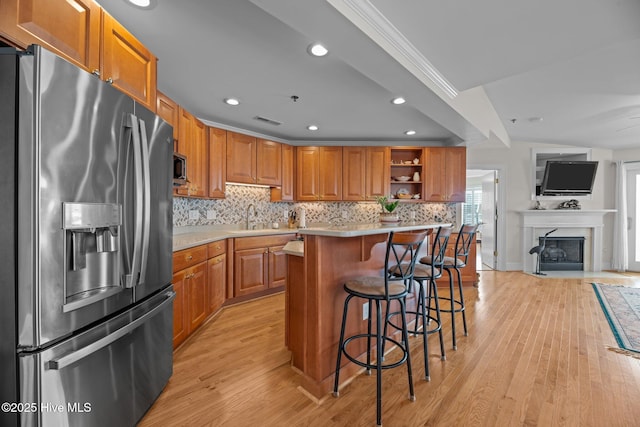 kitchen with a breakfast bar area, appliances with stainless steel finishes, a kitchen island, decorative backsplash, and light wood-type flooring