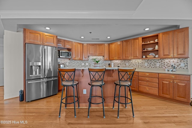 kitchen with a breakfast bar area, light hardwood / wood-style flooring, appliances with stainless steel finishes, ornamental molding, and a kitchen island