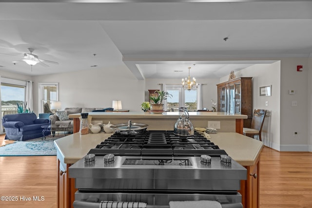 kitchen with lofted ceiling, a healthy amount of sunlight, ceiling fan with notable chandelier, and light hardwood / wood-style flooring