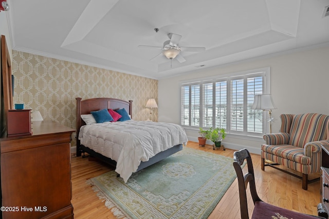 bedroom featuring ceiling fan, a tray ceiling, and light hardwood / wood-style flooring