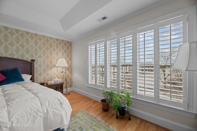 bedroom featuring multiple windows, crown molding, hardwood / wood-style floors, and a tray ceiling