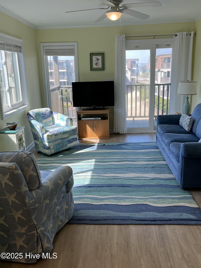 living room with wood finished floors, a ceiling fan, and crown molding