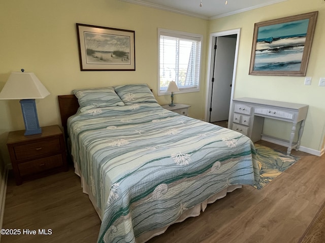 bedroom with baseboards, wood finished floors, and crown molding