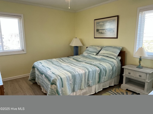 bedroom with multiple windows, ornamental molding, and wood finished floors