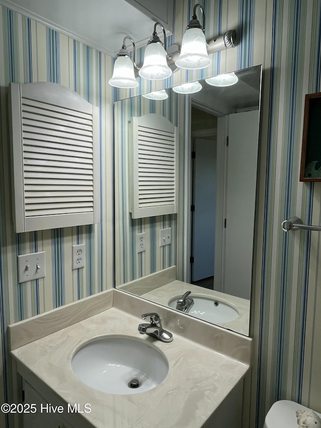 bathroom featuring wallpapered walls and vanity