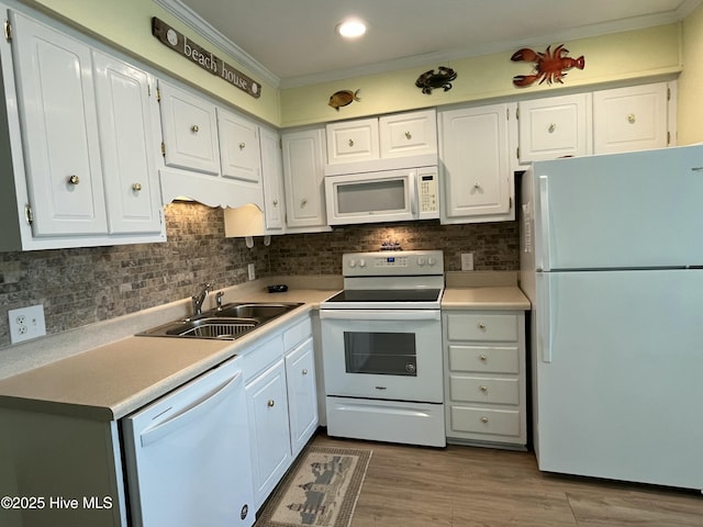 kitchen with white appliances, crown molding, white cabinets, and a sink