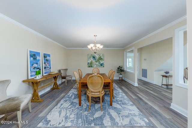 dining space with ornamental molding, hardwood / wood-style floors, and an inviting chandelier