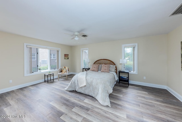 bedroom with multiple windows, light hardwood / wood-style floors, and ceiling fan