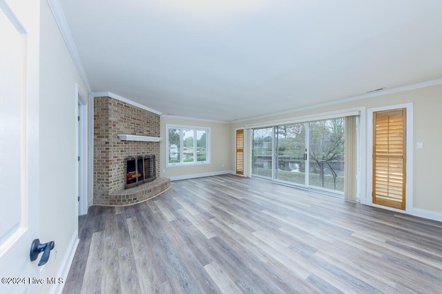 unfurnished living room with ornamental molding, a brick fireplace, and light wood-type flooring