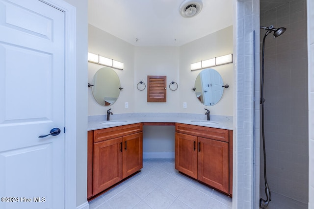 bathroom featuring tile patterned flooring, vanity, and a tile shower