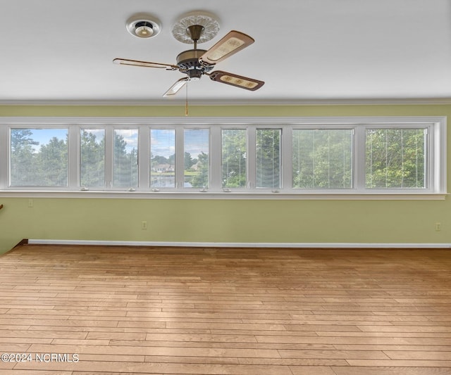 unfurnished room with light hardwood / wood-style flooring, plenty of natural light, ornamental molding, and ceiling fan