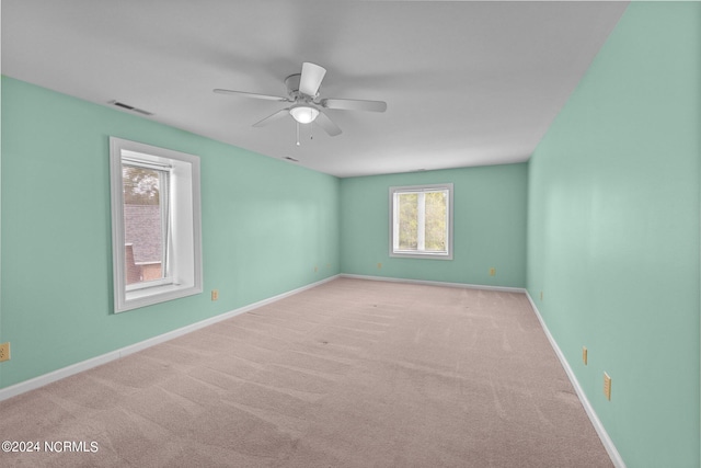 carpeted spare room featuring a wealth of natural light and ceiling fan