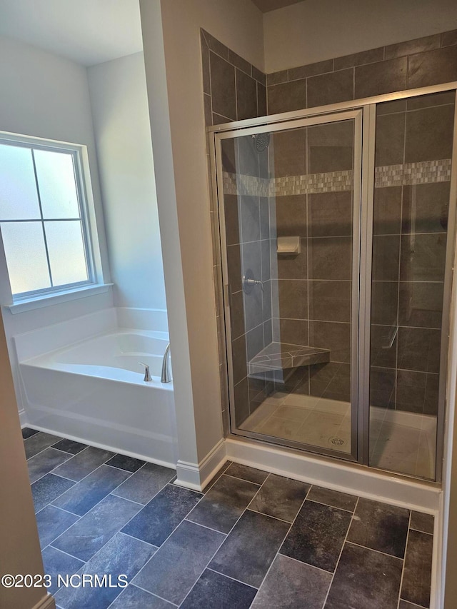 bathroom with shower with separate bathtub and tile flooring