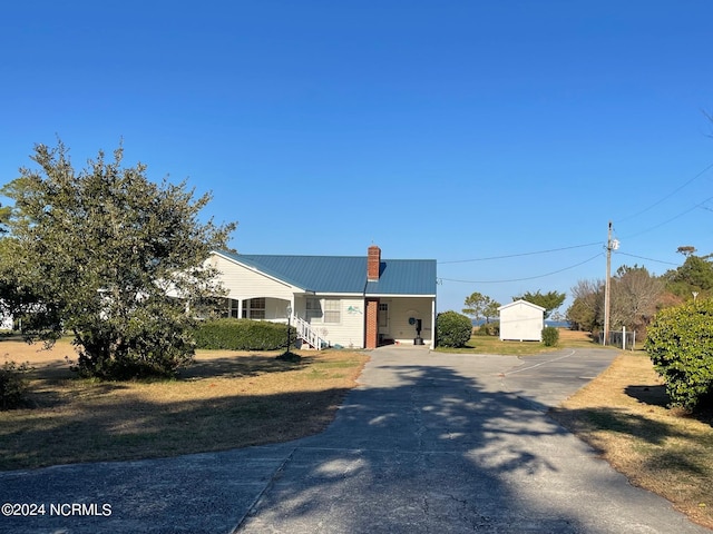 view of front of home featuring a chimney, metal roof, and a front yard