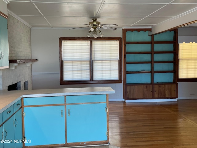 kitchen with ceiling fan, wood finished floors, light countertops, blue cabinetry, and a brick fireplace