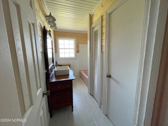 full bath featuring a washtub, wood walls, and vanity