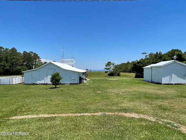 view of yard with a pole building, fence, and an outdoor structure